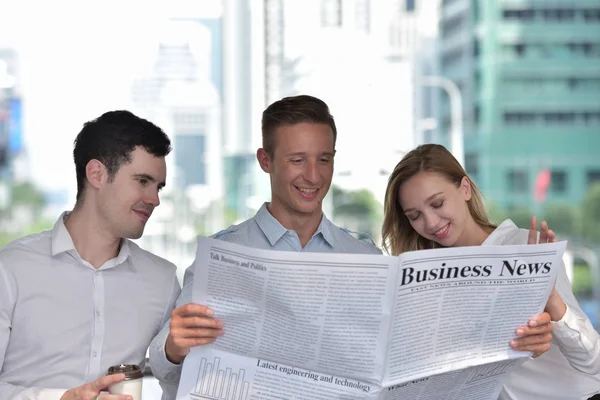 Three business people is reading newspaper and discussing in city center