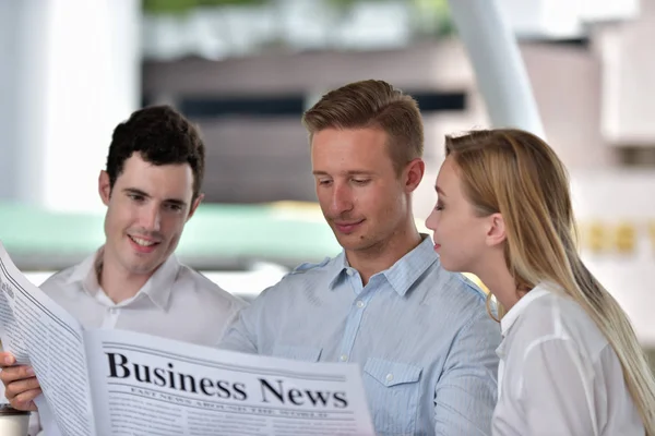 Three business people is reading newspaper and discussing in city center