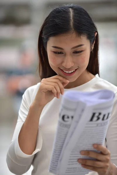 Asian woman reading newspaper
