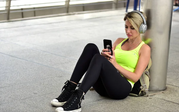 Sports woman listening music on mobile phone in headphones
