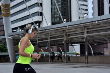 Şehirde koşan sporcu bir kadın var.