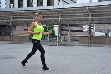 Şehirde koşan sporcu bir kadın var.