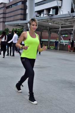 Şehirde koşan sporcu bir kadın var.