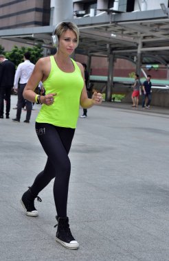 Şehirde koşan sporcu bir kadın var.