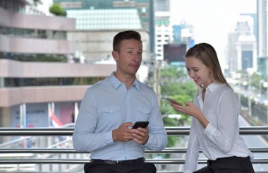 İş adamı ve iş kadını cep telefonu kullanıyor