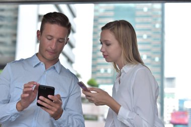 İş adamı ve iş kadını cep telefonu kullanıyor
