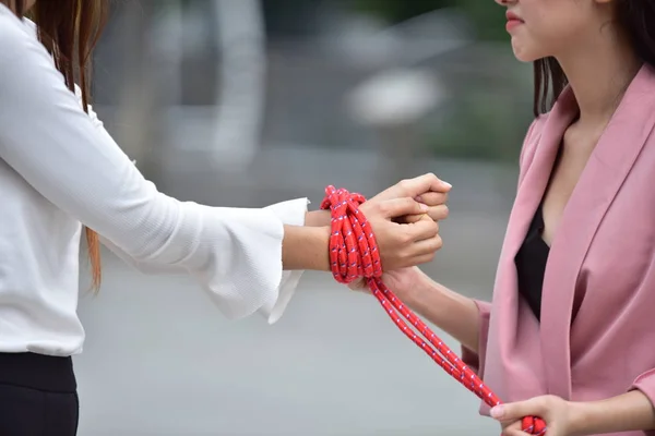 Asian women is tying hands with a rope