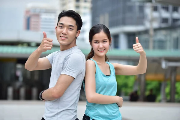 Happy asian sports couple showing thumbs up