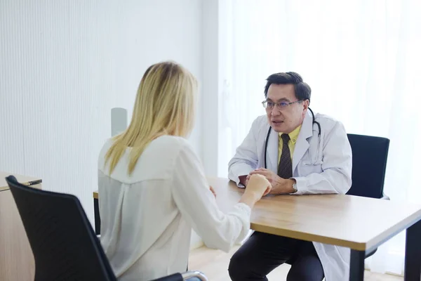 Doctor is talking with woman patient at table