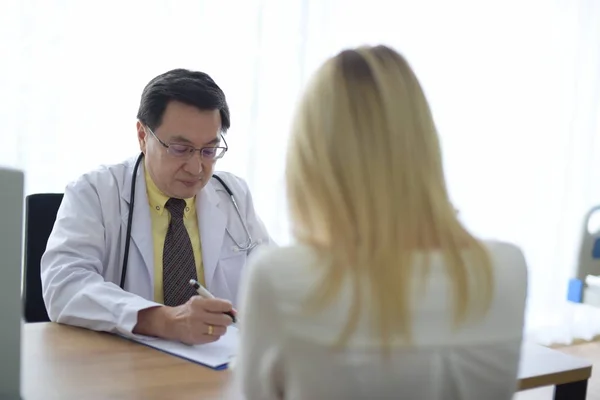 Doctor is talking with woman patient at table