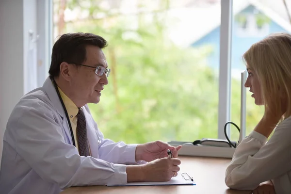 woman talking to doctor psychiatrist in hospital,Discuss issue and find solutions to mental health problems.Young beautiful woman suffering from headache desperate and stressed.