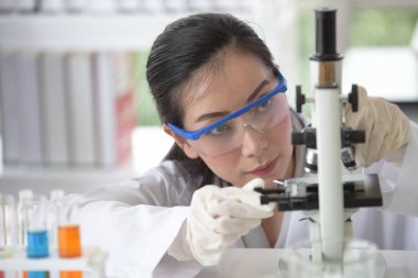 Genç kadınlar bilim adamları bilim laboratuvarı ile çalışıyoruz. Bir test tüpünde bir laboratuvarda tutan Asya bilim adamı