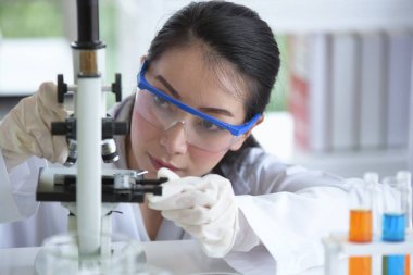 Genç kadınlar bilim adamları bilim laboratuvarı ile çalışıyoruz. Bir test tüpünde bir laboratuvarda tutan Asya bilim adamı