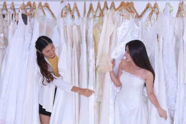 Asyalı gelin butikte danışman eşliğinde gelinlik seçiyor.