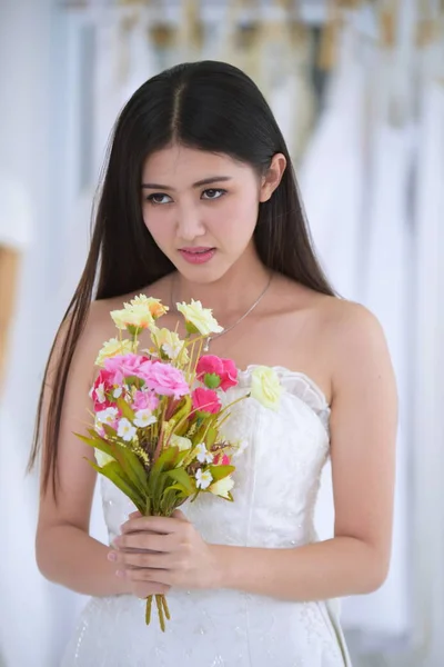 Asian bride in wedding dress with bouquet of flowers