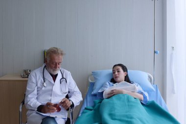 Doktor, hastanedeki hastalara ilaç gösteriyor.
