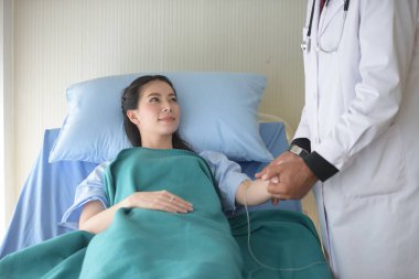 Doktor hasta odasında el ele tutuşuyor.