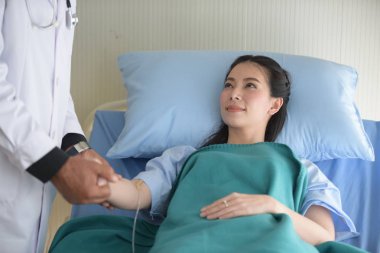 Doktor ilgilenir ve genç kadın hasta ile izleme ve onay için ameliyattan sonra konuşurken hospital.cheerful Doktor hastaya teşvik eder.