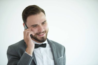 Zarif kostümlü genç beyaz adam cep telefonuyla konuşuyor.