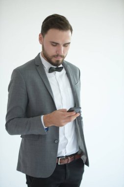 Zarif kostümlü genç beyaz adam cep telefonu kullanıyor.