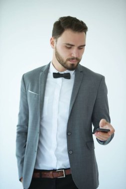 Zarif kostümlü genç beyaz adam cep telefonu kullanıyor.