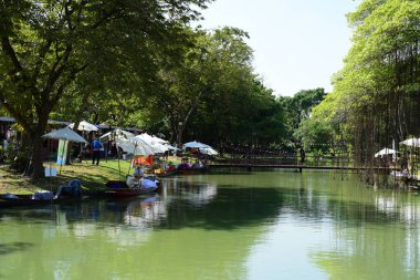 İnsanlar parkta göl kenarında dinleniyor.