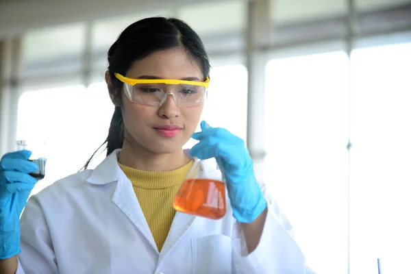 Young scientists are experimenting with science at Asian scientist holding a test tube in a laboratory. Scientists are working in science labs.