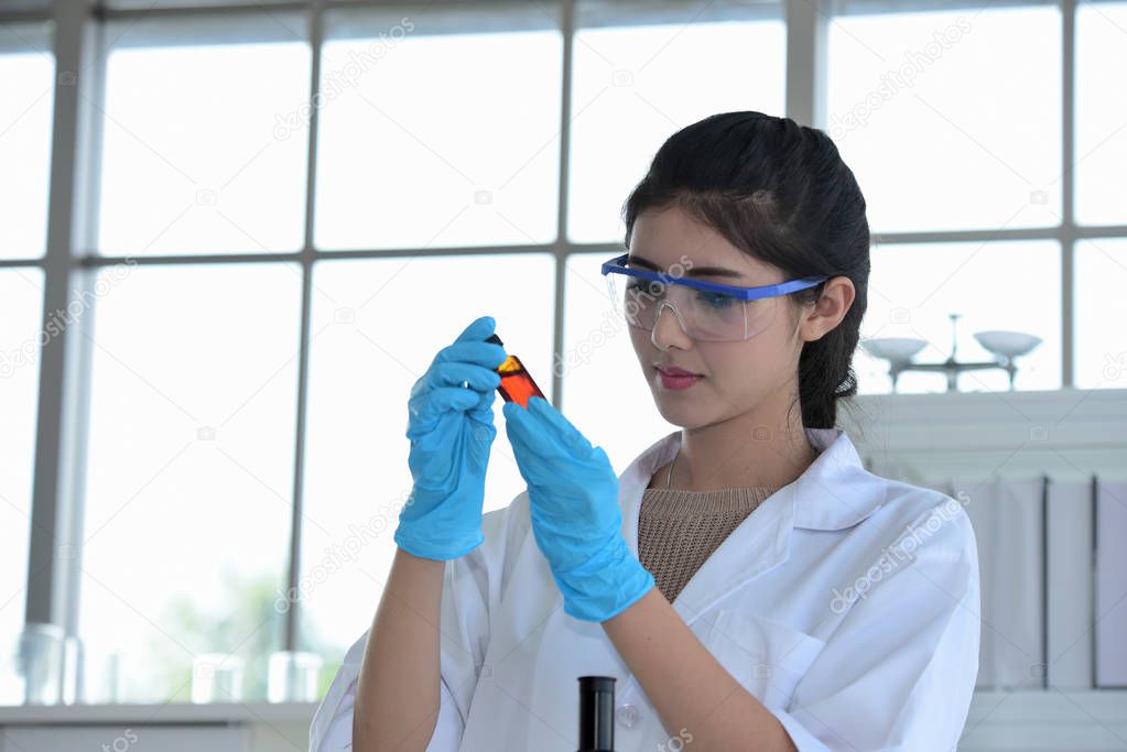 Young scientists are experimenting with science at Asian scientist holding a test tube in a laboratory. Scientists are working in science labs. 