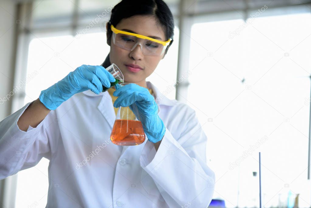 Young scientists are experimenting with science at Asian scientist holding a test tube in a laboratory. Scientists are working in science labs. 