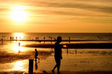 Gün batımında güzel sahil manzarasında birçok insan gün batımından önce oynamak için sahile gelirler..