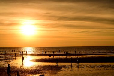 Gün batımında güzel sahil manzarasında birçok insan gün batımından önce oynamak için sahile gelirler..
