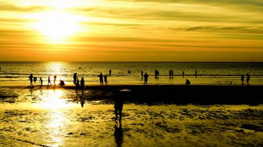 Gün batımında güzel sahil manzarasında birçok insan gün batımından önce oynamak için sahile gelirler..