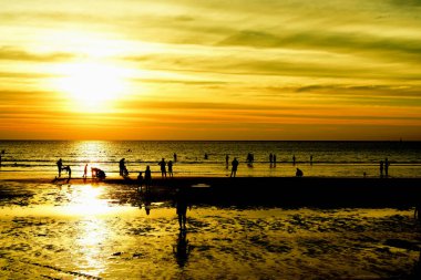 Gün batımında güzel sahil manzarasında birçok insan gün batımından önce oynamak için sahile gelirler..