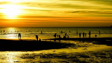 Gün batımında güzel sahil manzarasında birçok insan gün batımından önce oynamak için sahile gelirler..