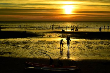 Gün batımında güzel sahil manzarasında birçok insan gün batımından önce oynamak için sahile gelirler..