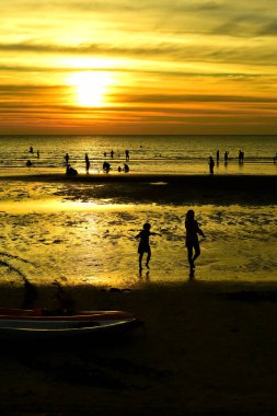 Gün batımında güzel sahil manzarasında birçok insan gün batımından önce oynamak için sahile gelirler..