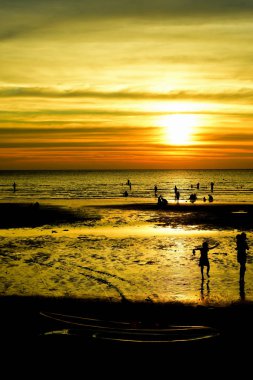 Gün batımında güzel sahil manzarasında birçok insan gün batımından önce oynamak için sahile gelirler..