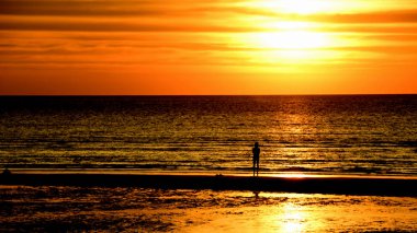 Gün batımında güzel sahil manzarasında birçok insan gün batımından önce oynamak için sahile gelirler..