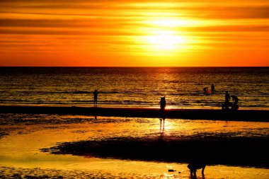 Gün batımında güzel sahil manzarasında birçok insan gün batımından önce oynamak için sahile gelirler..