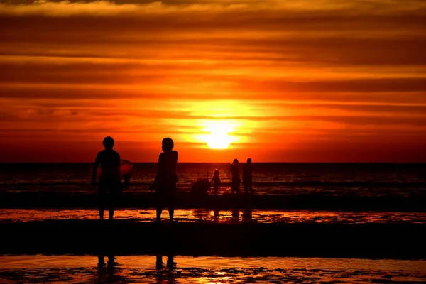 许多人在黄昏前来到海里玩耍 海滩上日落的轮廓 — 图库照片