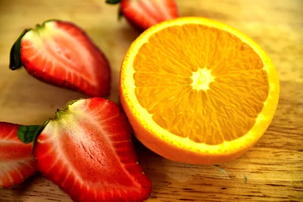 chopped orange and strawberries on wooden board