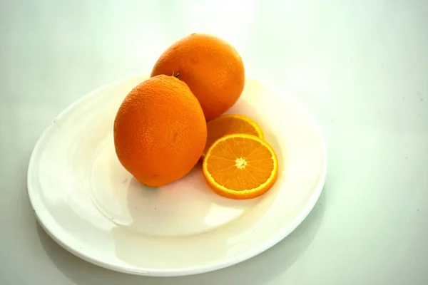 Orange, half of orange, orange lobule and basket with oranges on the wooden table on the green blurred background.Composition with variety of fruits.dieting concept,