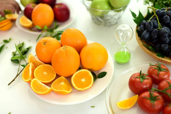 Orange, half of orange, orange lobule and basket with oranges on the wooden table on the green blurred background.Composition with variety of fruits.dieting concept,