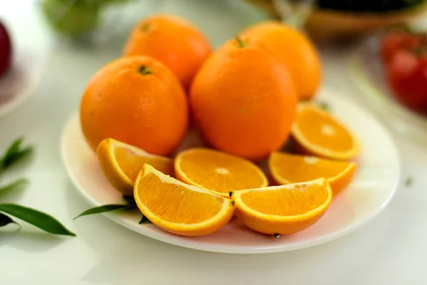 Orange, half of orange, orange lobule and basket with oranges on the wooden table on the green blurred background.Composition with variety of fruits.dieting concept,