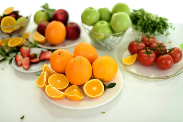 Orange, half of orange, orange lobule and basket with oranges on the wooden table on the green blurred background.Composition with variety of fruits.dieting concept,