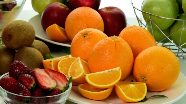 Orange, half of orange, orange lobule and basket with oranges on the wooden table on the green blurred background.Composition with variety of fruits.dieting concept,