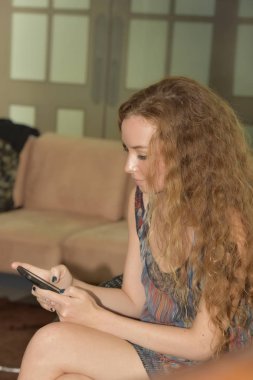 Oturma odasında cep telefonu kullanan bir kadın. 