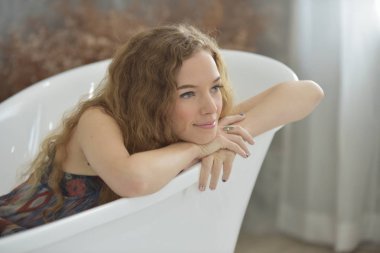 Genç kadın bathroom.young kadın küvette rahatlatıcı bathtub.relaxed zamanında döşeme. Tatlı bir gülümseme ile güzel bir kadın. Rahatlatıcı bir günde güzel bir duruş