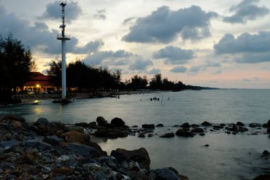 Bulutlu gün batımı gökyüzü ile kayalık sahil