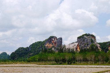 Yeşil ve mavi bulutlu gökyüzü ile kayalık arazi